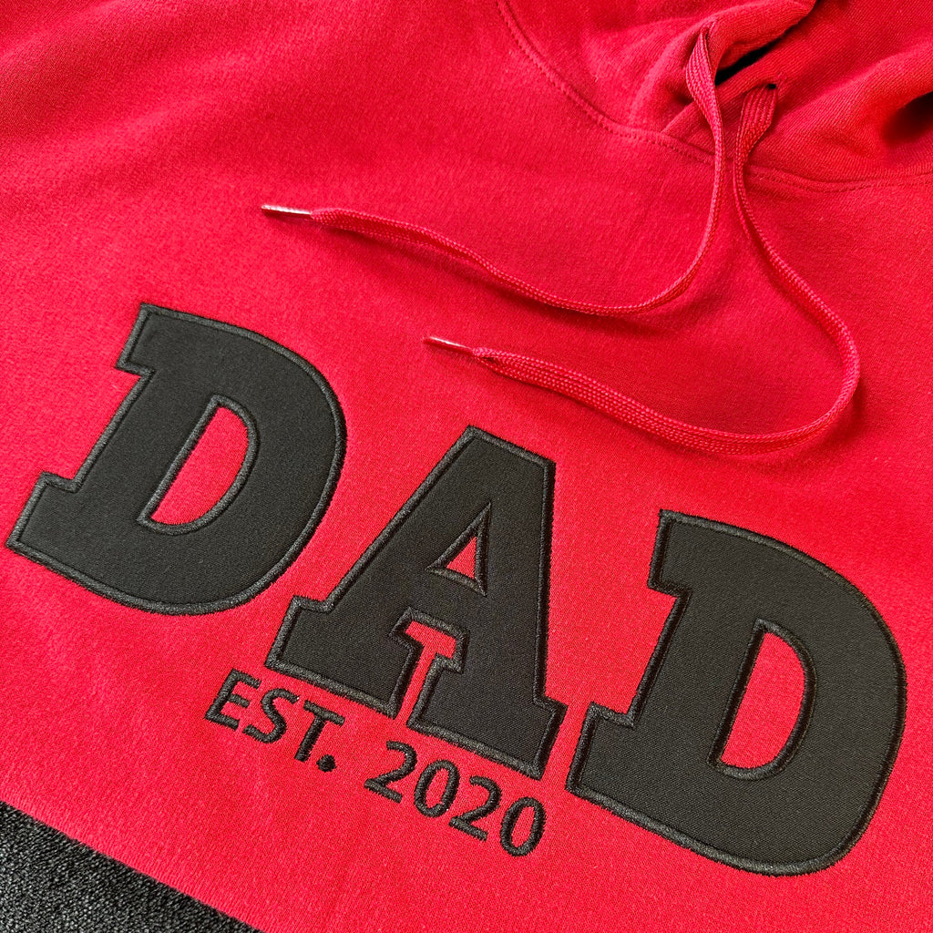Red hoodie with 'DAD EST. 2020' text